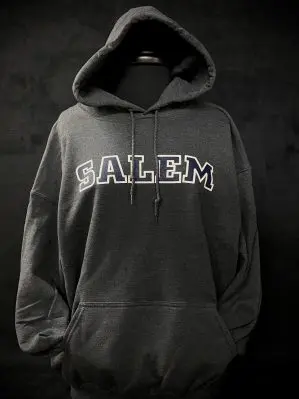 Image of a gray hoodie in front of a black background with 'Salem' across the front of the hoodie. The font is blue with a white outline.