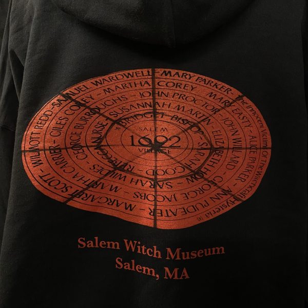 Back side of red circle hoodie which features the red circle with the 1692 victims names along with 'Salam Witch Museum' written beneath it.