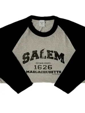 Photo of Black Baseball Style tee with 'Salem Massachusetts' written on the front. 1626 written below. Main body is gray, sleeves and collar are black.