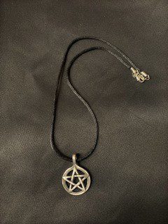 Pewter pentagram necklace. Pendant is suspended on a black cord. Made in USA.