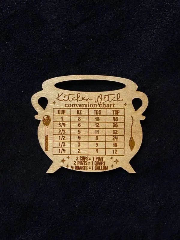 An engraved wooden magnet in the shape of a cauldron. The words "Kitchen Witch Conversion Chart" are across the top. Converts between cups, ounces, tablespoons, and teaspoons, as well as pints, quarts, and gallons.
