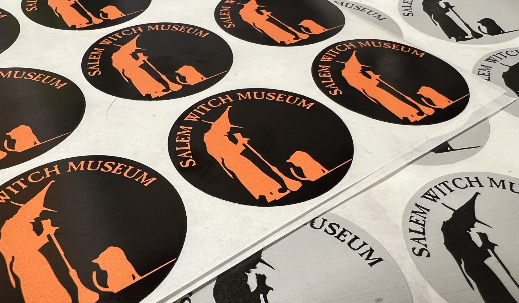 Black and orange stickers and grey and black stickers used for tickets and discounts and discount partners with the Salem Witch Museum logo.
