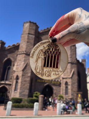 Photo showcasing our red window suncatcher ornament with the museum as backdrop. More detailed alt text describing the ornament is attached to the next image.